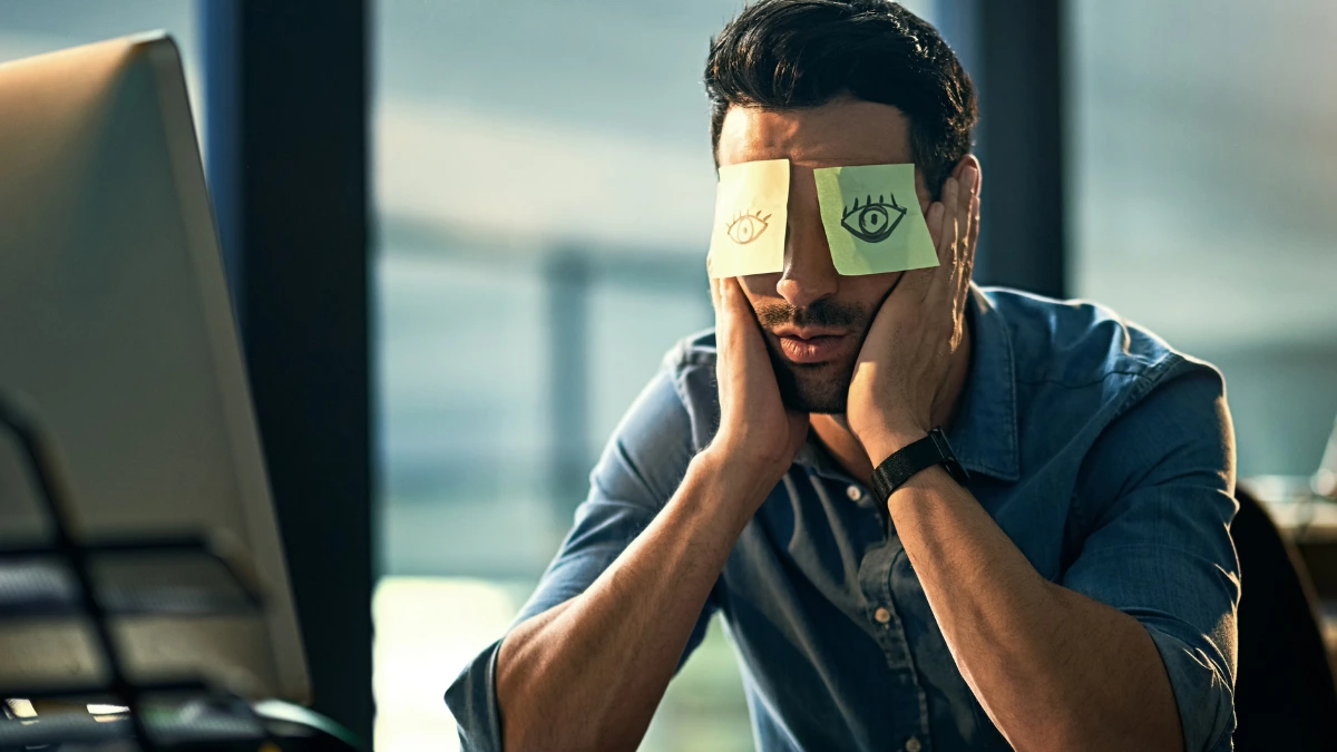 dr.consulta - Na imagem, homem cansado e com incômodo ocular por pressão no olho. Em seu rosto, dois post its estão colados nos olhos.