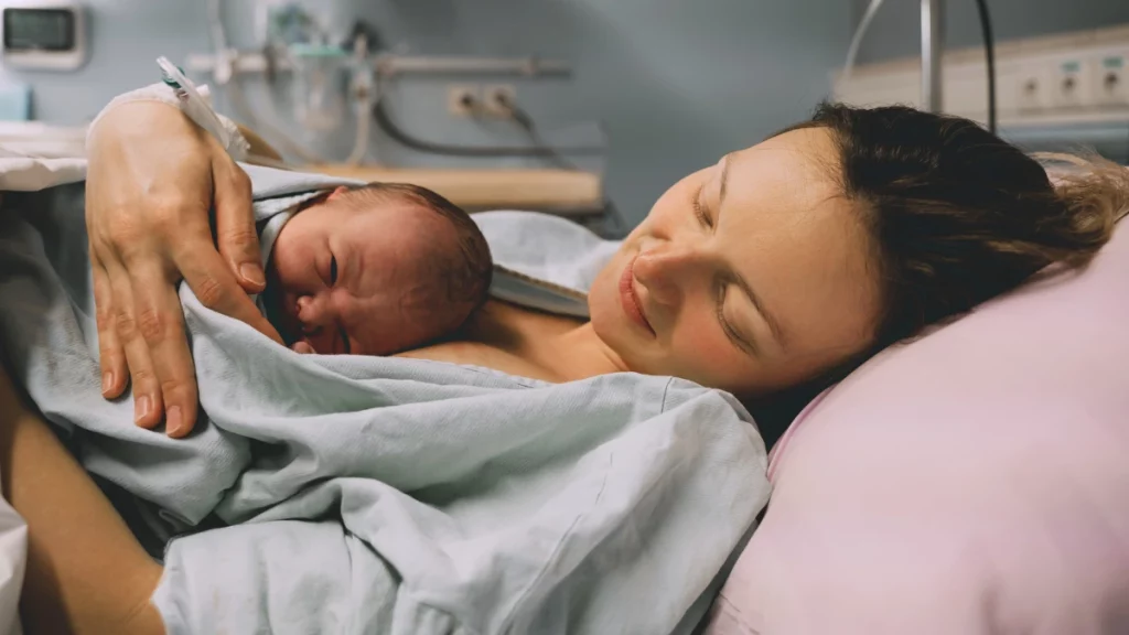 dr.consulta - Na imagem, mulher deitada segura recém-nascido no colo aguardando para o teste do olhinho.