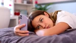 dr.consulta - jovem deitada na cama olhando para o celular que está em suas mãos, ansiedade em adolescentes