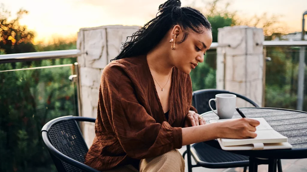 dr.consulta - Mulher sentada em mesa ao ar livre lendo anotações no caderno para ajudar a melhorar a memória.