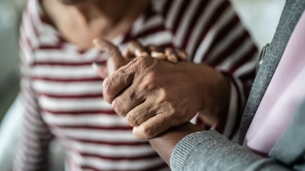 dr.consulta - Pessoa com doença de Parkinson recebendo apoio e sendo amparada, representando cuidado e acolhimento.