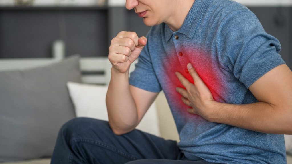 Homem tossindo com a mão no peito