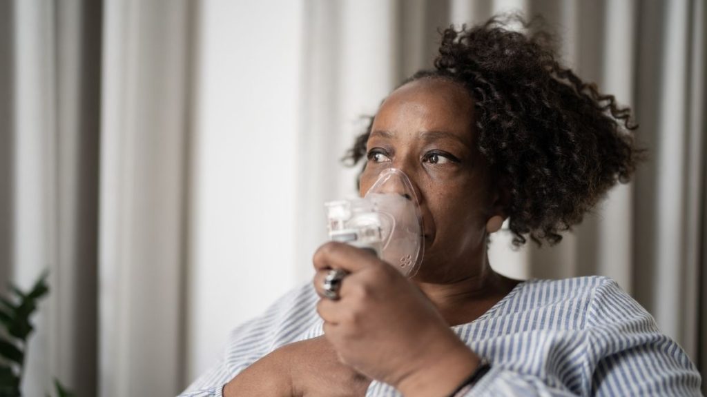 Mulher com bronquite segurando máscara de nebulização