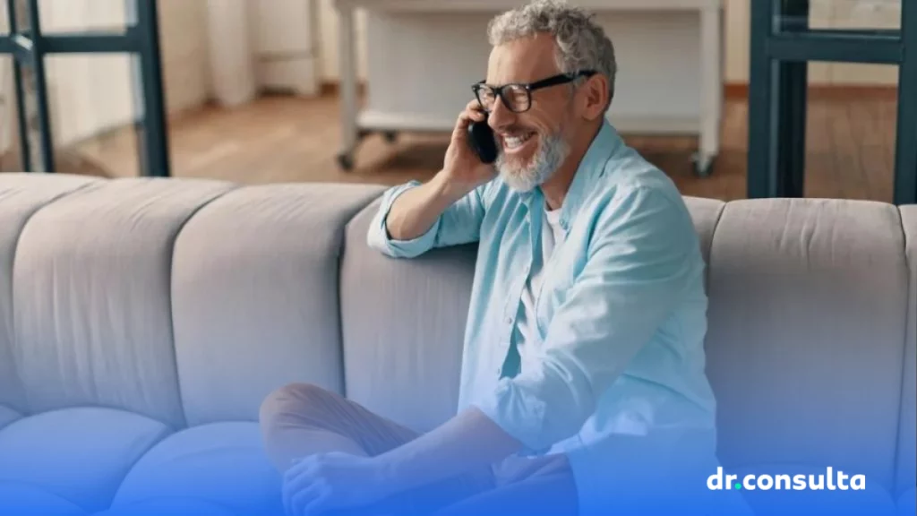 dr.consulta - homem branco, sentado no sofá sorrindo e falando ao telefone ligando no telefone do dr.consulta