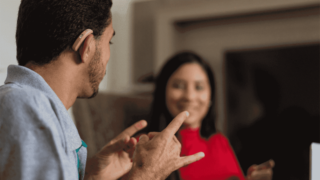 Pessoas se comunicando em língua de sinais por terem passado pela perda auditiva.