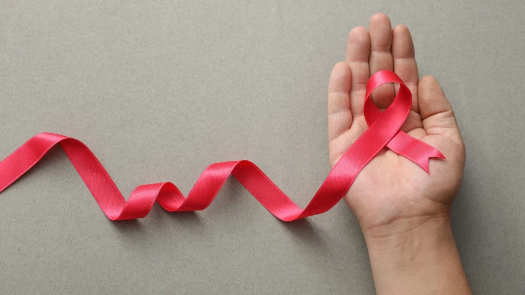 dr.consulta - Mão de homem segurando fita rosa. A imagem simboliza combate ao câncer de mama masculino.