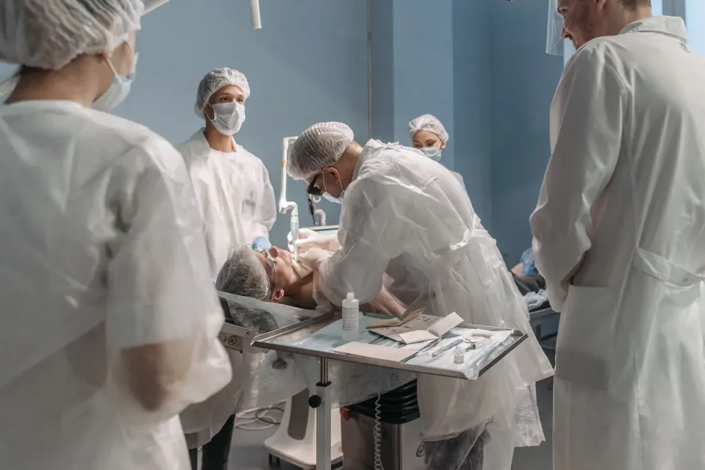 Na imagem observamos uma equipe médica realizando o procedimento em uma sala cirúrgica de um hospital.