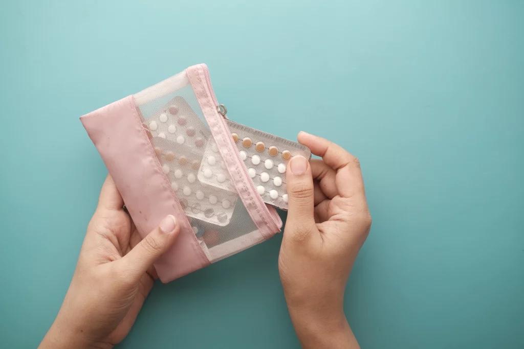  Imagem de uma mulher segurando uma bolsa transparente com cartelas de remédios anticoncepcionais.