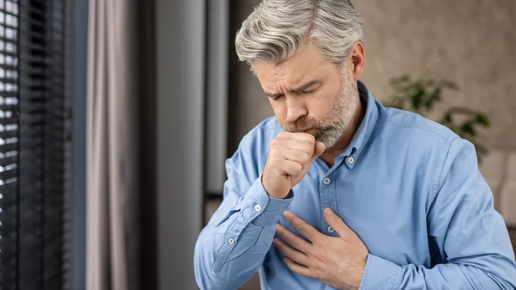 dr.consulta -  Homem de meia-idade com expressão de dor, tossindo e com a mão no peito, indicando sintomas de insuficiência cardíaca. 