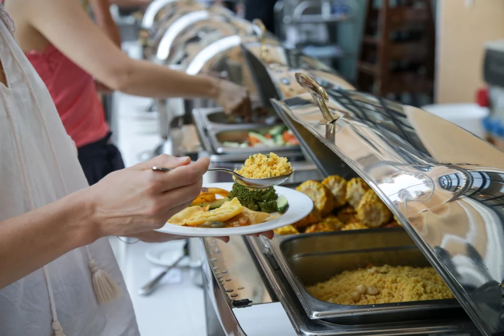 Imagem de uma pessoa se servindo em um buffet self service. 