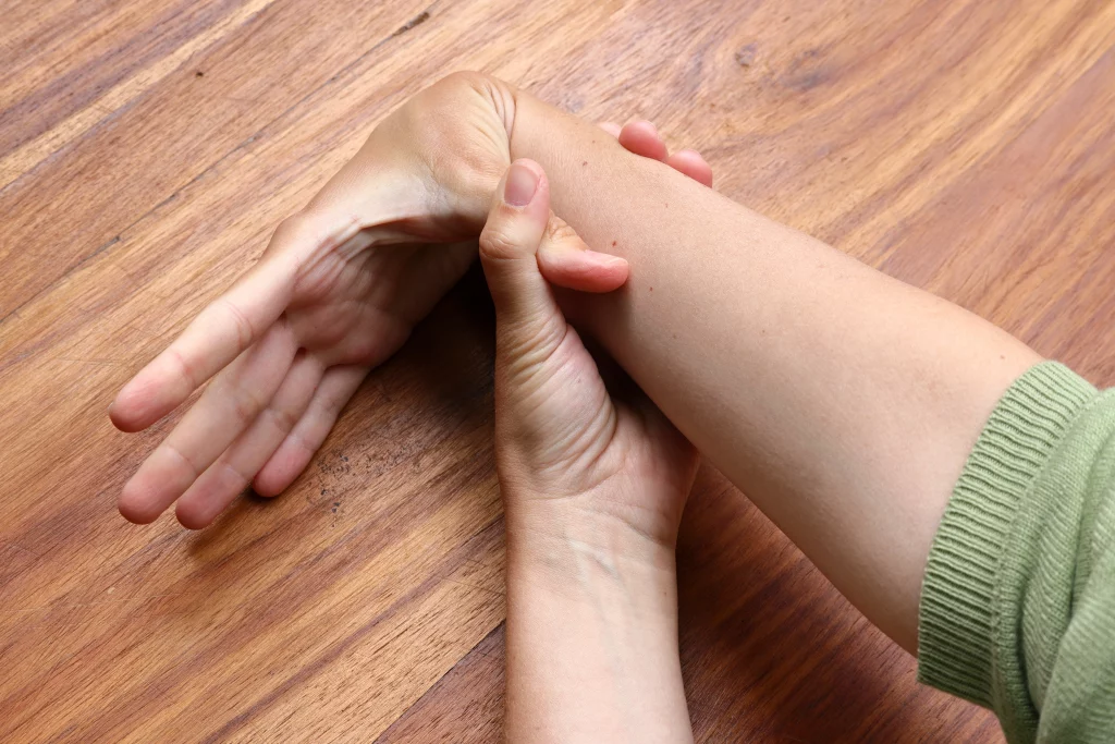 Imagem de uma pessoa branca demostrando flexibilidade na articulação do pulso ao encostar o dedão na parte interior do braço.