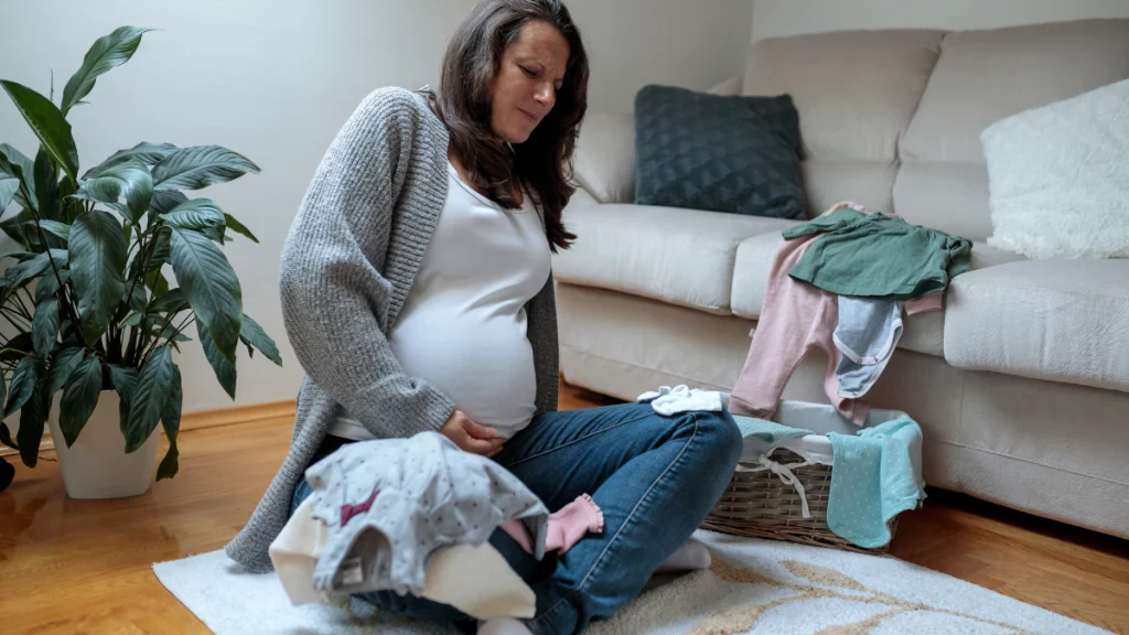 dr.consulta - mulher grávida sentada no chão da sala, separando o enxoval, início das contrações, maternidade, nascimento do bebê