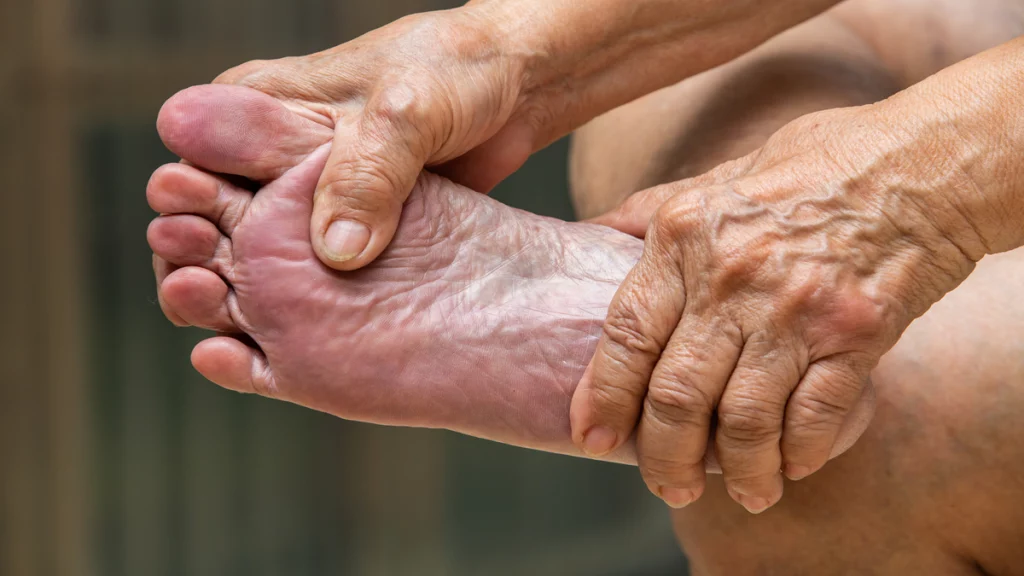 Imagem das pernas e pé de uma pessoa. Na foto, seu rosto não aparece, apenas suas mãos sob os pés.