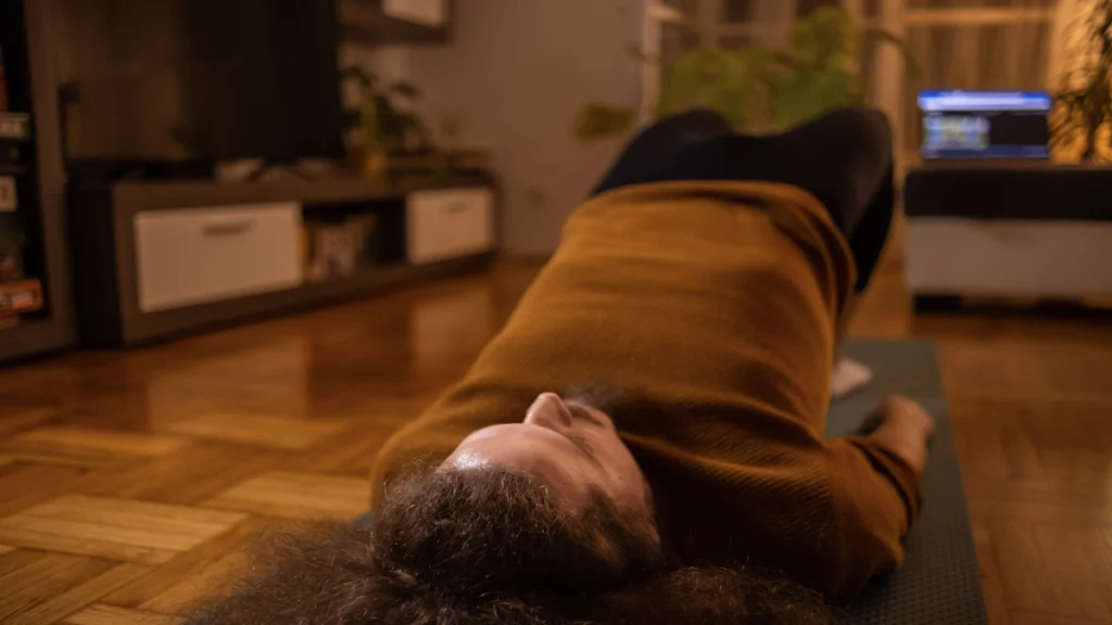 Imagem de um homem deitado no chão de uma sala fazendo exercícios de Kegel para homens.