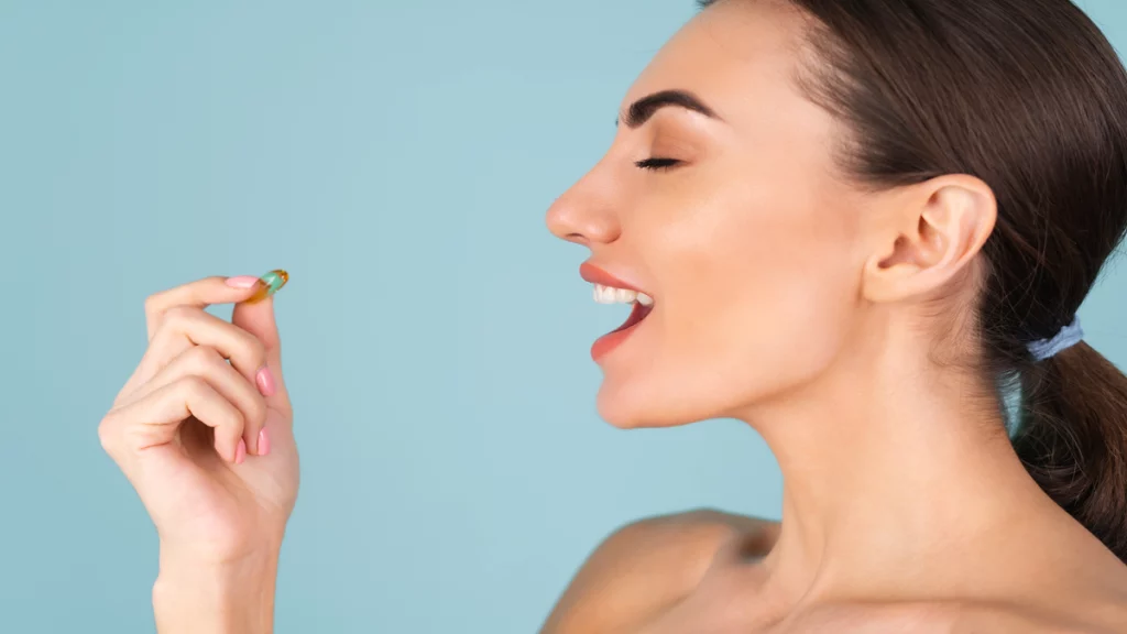 Imagem de uma mulher levando um comprimido de vitamina b12 na boca.