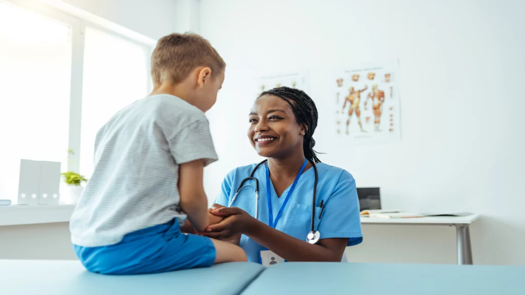 Imagem de uma profissional da saúde atendendo um menino em um consultório médico.