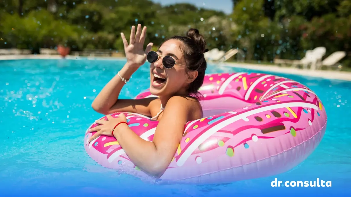 Imagem de uma mulher sorrindo em uma piscina. Também é possível ver uma boia em formato de donut.