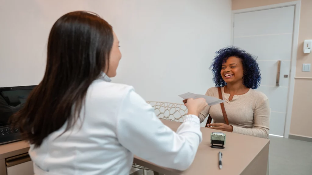 Imagem de uma mulher sendo atendida por uma profissional da saúde em um consultório médico.