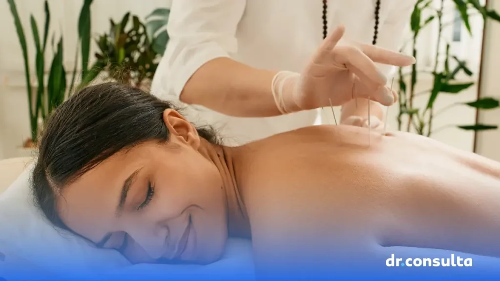 dr.consulta - mulher negra deitada de bruços, sorrindo relaxadamente, enquanto uma pessoa especialista está realizando acupuntura em suas costas.