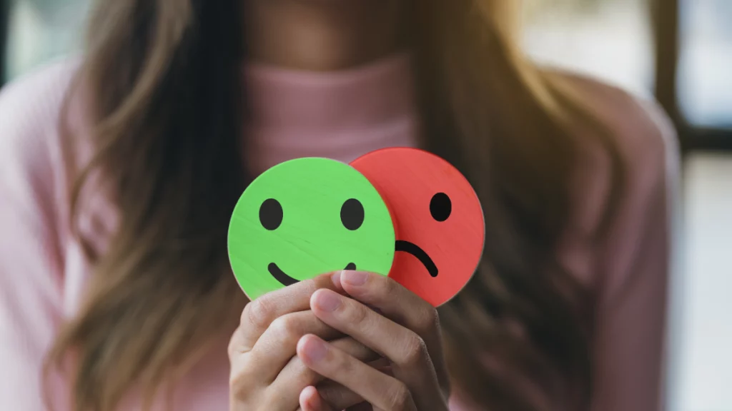 dr.consulta - mulher com emojis na mãos sinalizando a tristeza e a alegria, hormônios da felicidade, alteração de humor, impactos na saúde