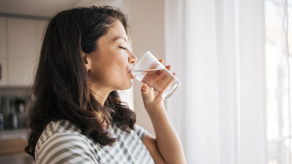 dr.consulta - Mulher bebendo um copo de água com expressão tranquila, representando hábitos saudáveis para emagrecer com saúde.