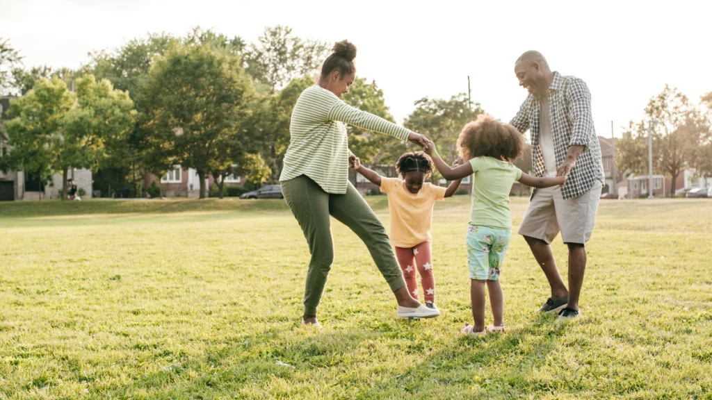 dr.consulta - família de pessoas negras com dois adultos e duas crianças fazendo ciranda em um parque, doenças autoimunes, anticorpos, sistema imunológico