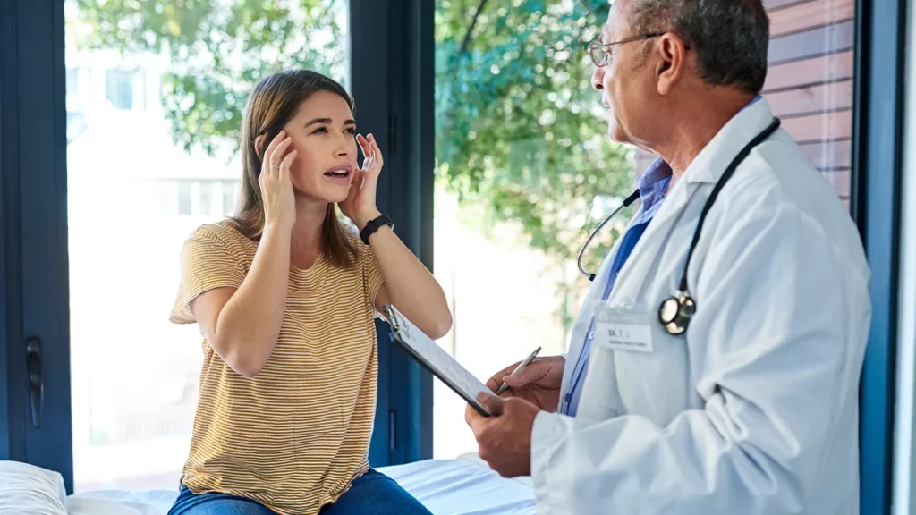 dr.consulta - mulher aponta os dedos para lateral da cabeça mostrando ao médico onde sente dor de enxaqueca