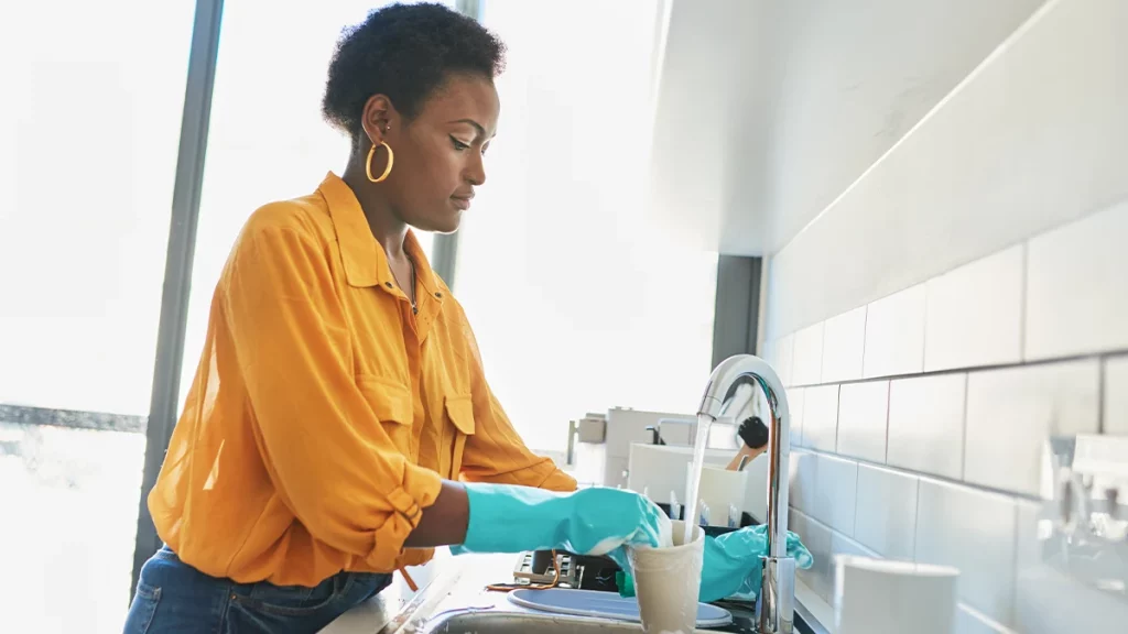 dr.consulta - mulher jovem com luvas nas mãos para evitar a disidrose enquanto lava louça 