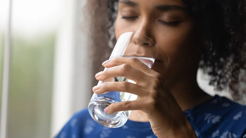 dr.consulta - mulher tomando um copo de água para se hidratar e minimizar os sintomas da síndrome de sjogren