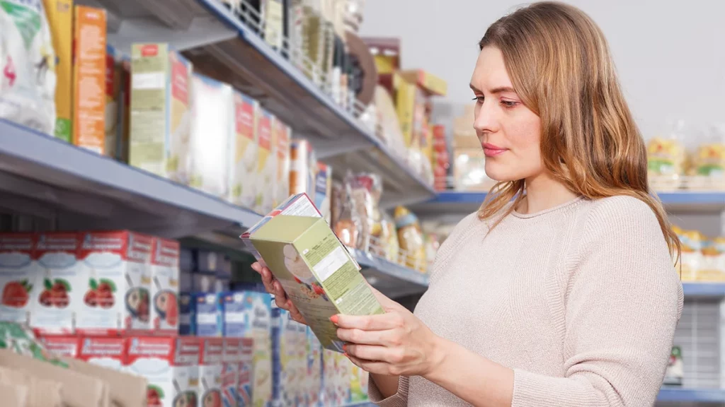 dr.consulta - mulher jovem com doença celíaca lendo o rótulo de alimentos no mercado para identificar alimentos sem glúten