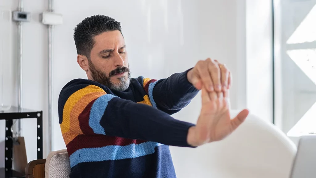 dr.consulta - homem de meia idade alongando os pulsos para reduzir o risco de Lesão por Esforço Repetitivo 