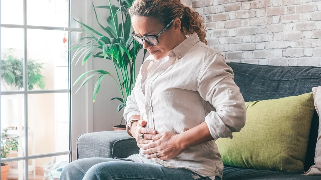 dr.consulta - mulher com as mãos na barriga, dor, sintomas do aneurisma da aorta abdominal