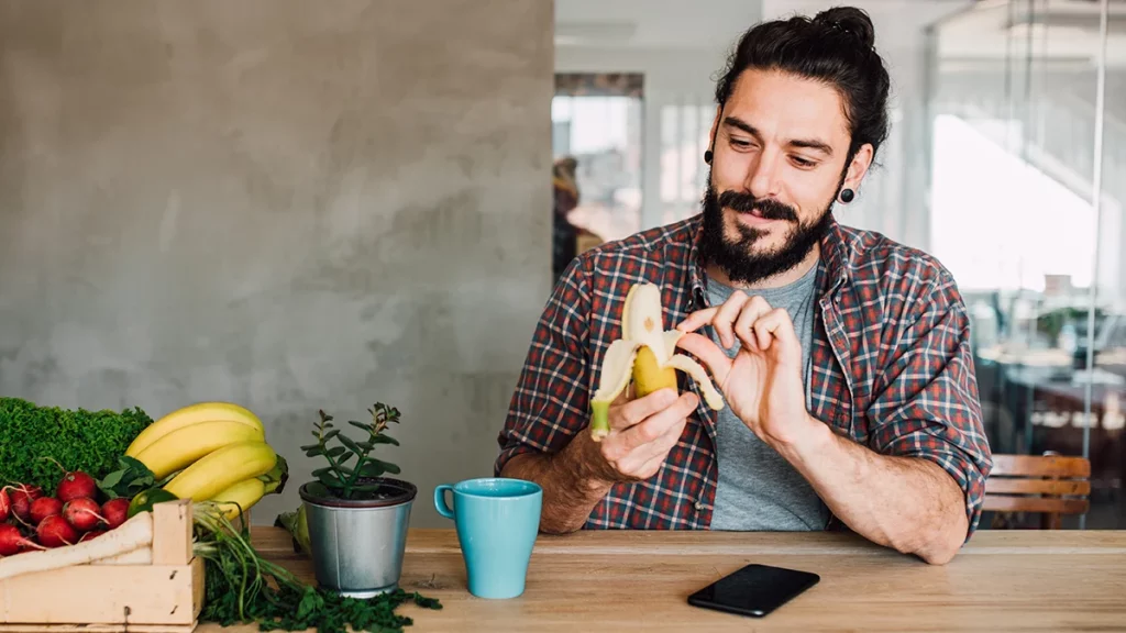 dr.consulta - Homem descascando uma banana, preocupado em manter uma alimentação saudável para o coração. 