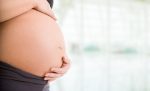 barriga de uma gestante no terceiro trimestre, com as mãos apoiadas suavemente sobre o ventre