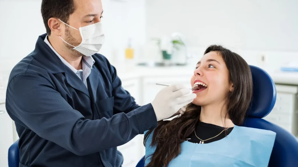 dr.consulta - Mulher com a boca aberta e deitada na cadeira do dentista. Na imagem, o profisisonal usa instrumentos para raspagem no dente