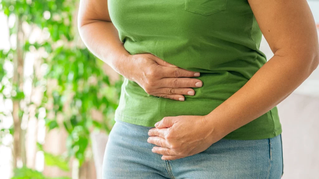 dr.consulta - Mulher tocando seu estômago por dor abdominal causada por diverticulose.